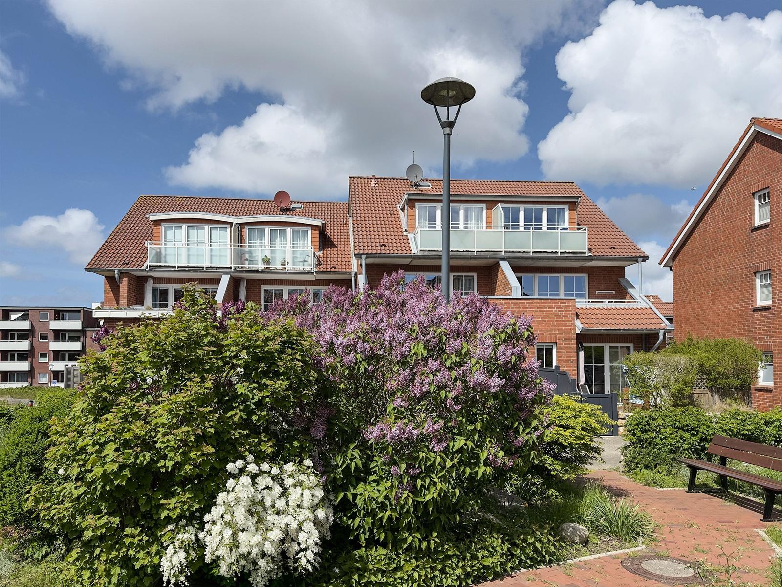 Rotes Backsteingebäude mit Balkonen und gepflasterter Gartenweg.