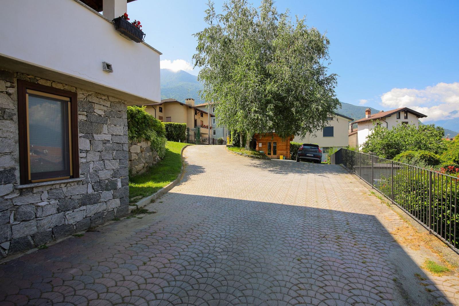 Haus mit Terrasse, Garten und Palmen unter blauem Himmel.