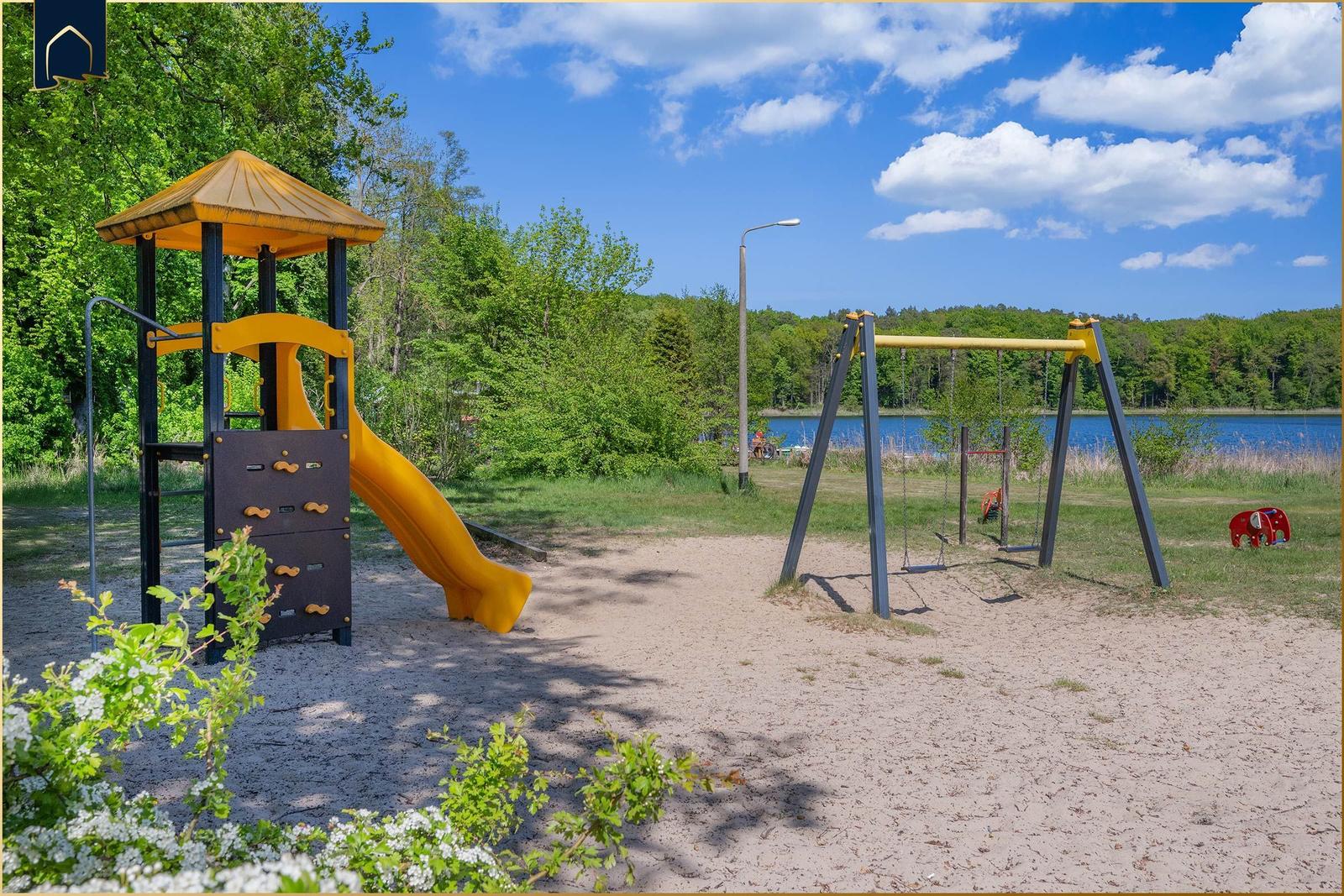 Zwei Fahrräder stehen am Strand. Zwei Personen sitzen auf einer Bank und blicken auf den See.
