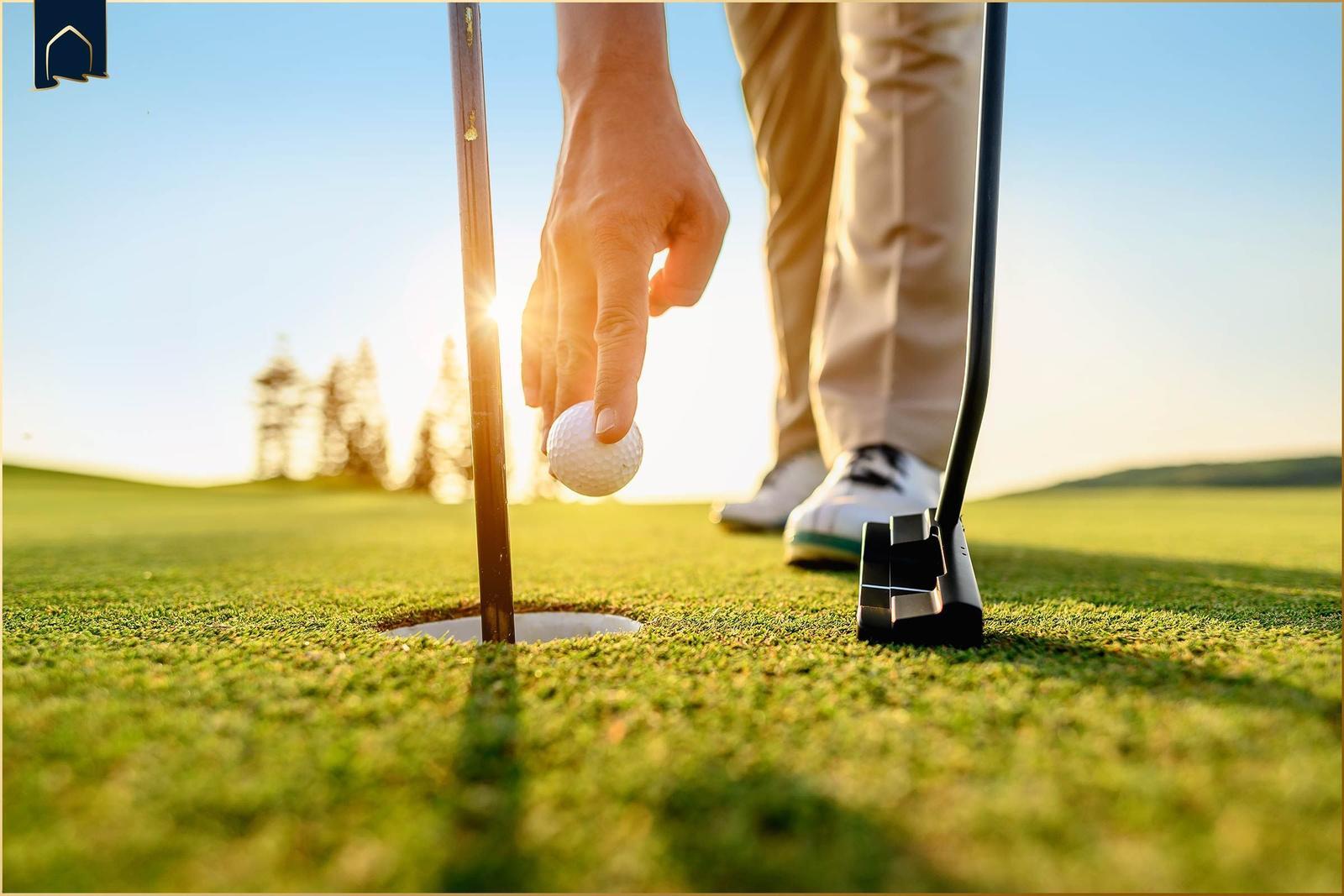 Mann schlägt Golfball, Frau beobachtet auf grünem Platz.