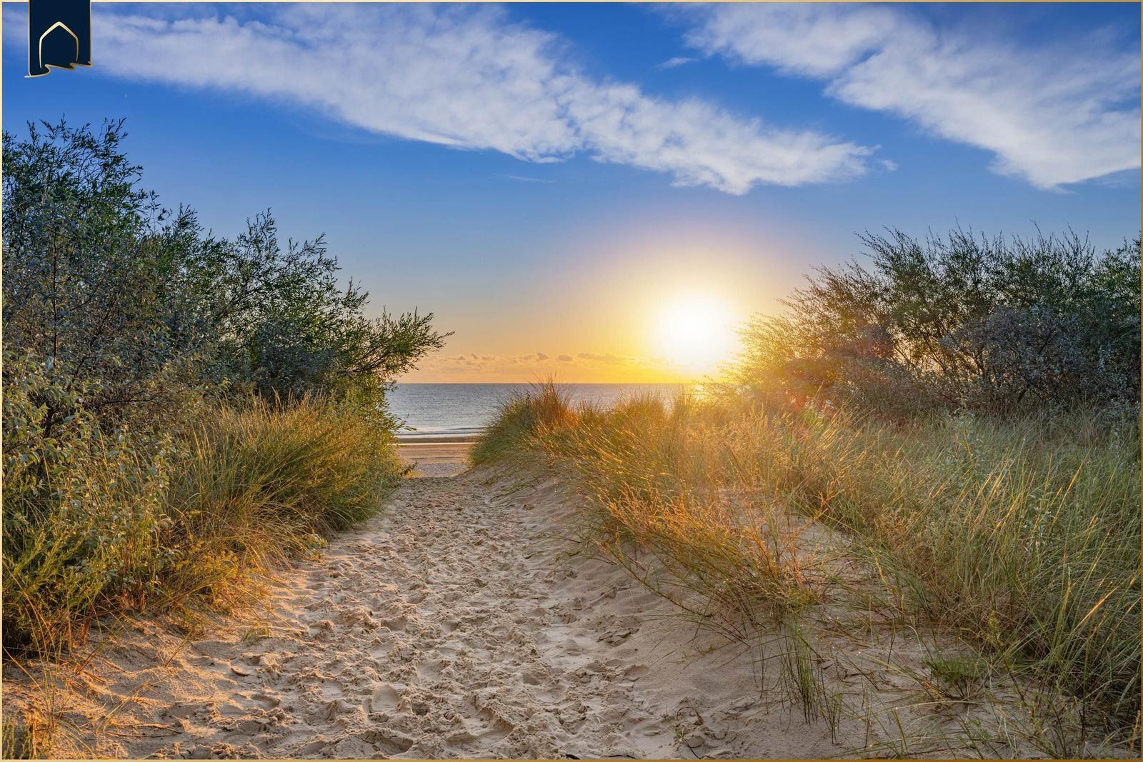 Drei weiße Strandkörbe mit Nummern stehen am Strand bei Sonnenuntergang.