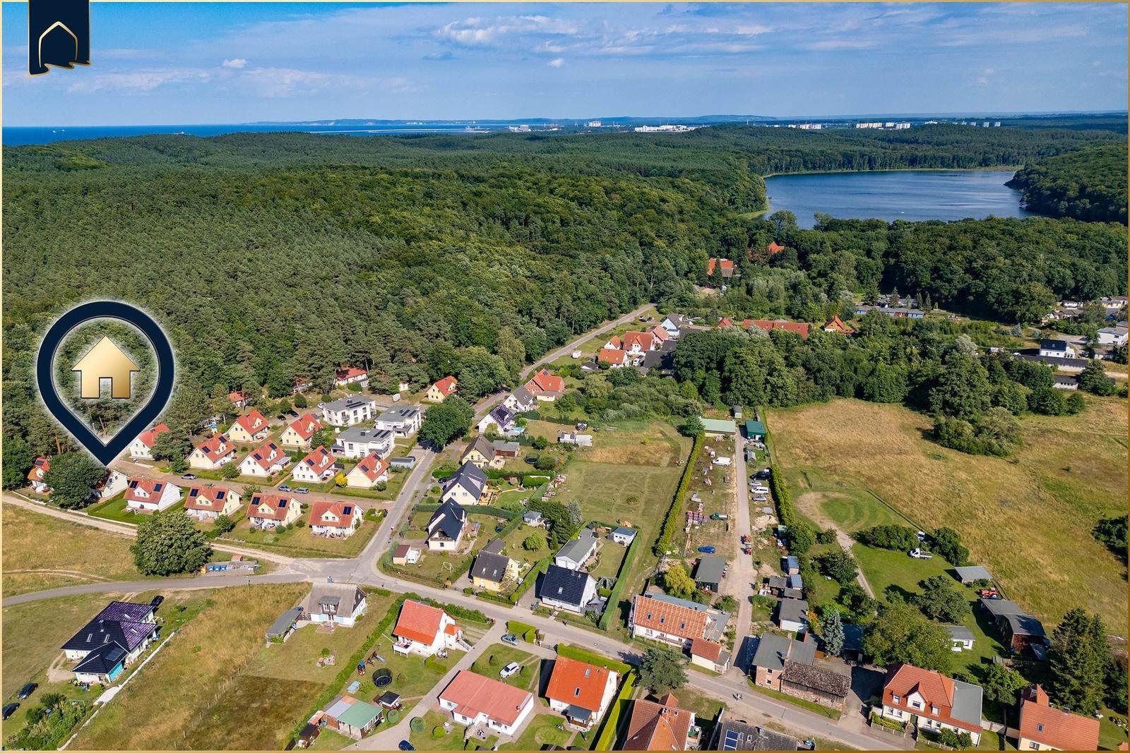 Zwei Bänke am Strand eines Sees mit grüner Umgebung und blauem Himmel.
