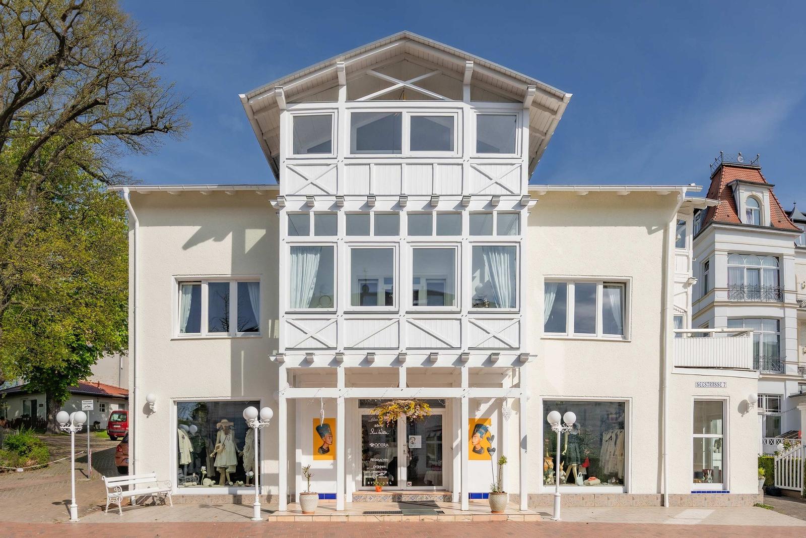 House with white wood cladding and large windows on a sunny day.