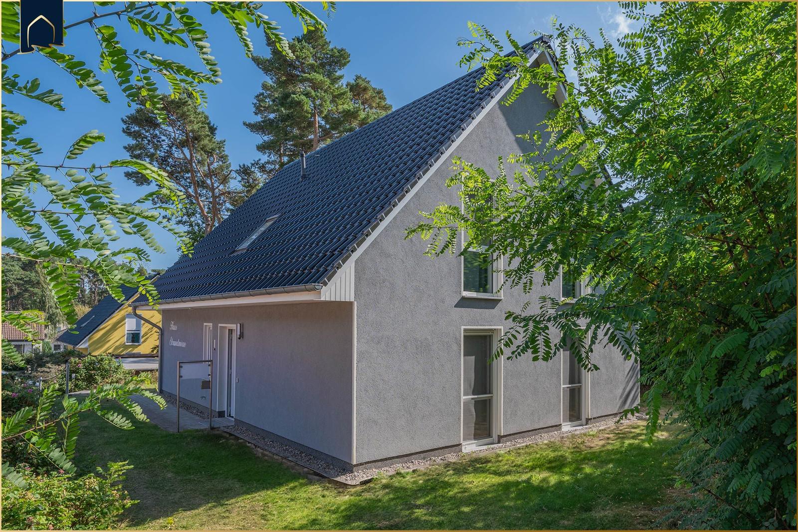 Hinterhof mit Spielplatz, Schaukel, Tipi und Rutschbahn zwischen Bäumen.