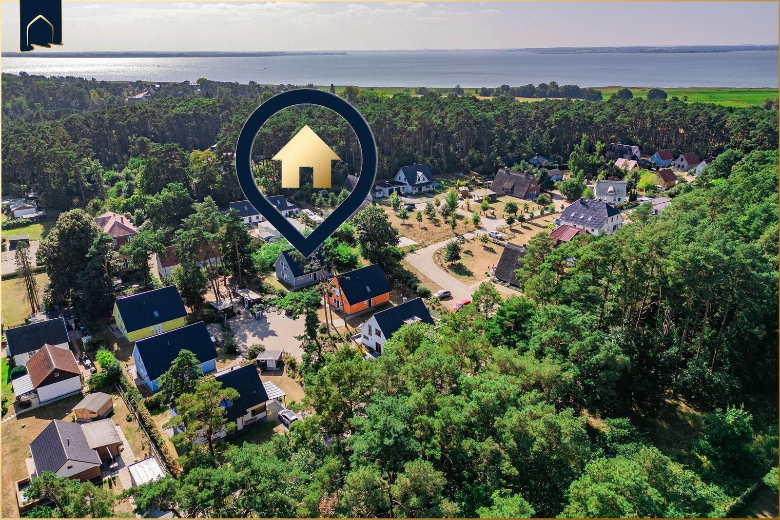 Luftbild einer Wohngegend mit Wald, Feldern und Blick aufs Meer.