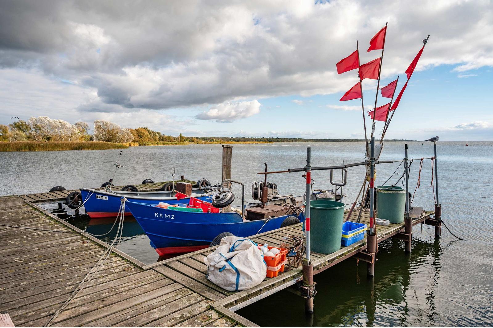 Holzbank am Ufer mit Blick auf See und Himmel.