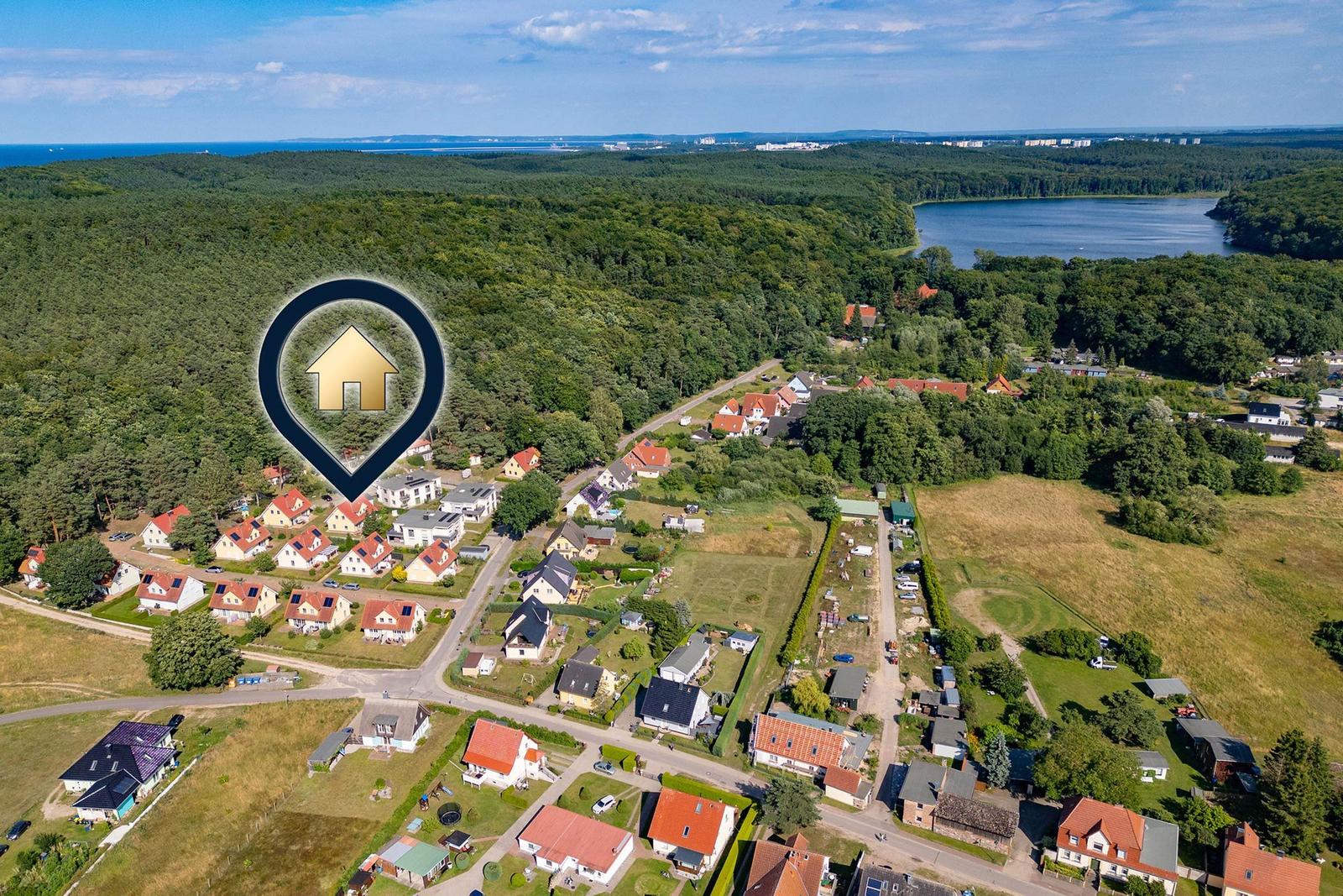 Zwei Bänke am Strand eines Sees mit Wald im Hintergrund.