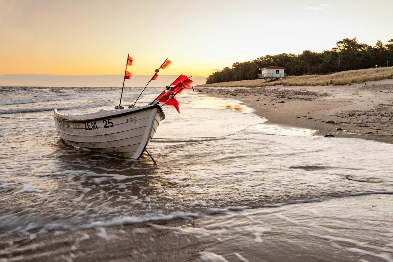 Bootshaken, Seile und Ruder liegen an einem Flussufer. Hintergrund: Bootsanlegestelle mit Booten.