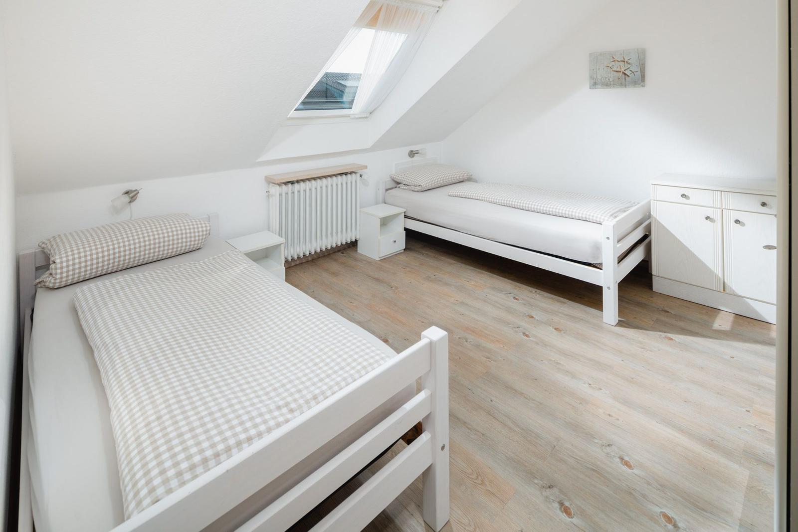 Zimmer mit zwei Betten, Holzboden und Kleiderschrank mit Spiegeltür.