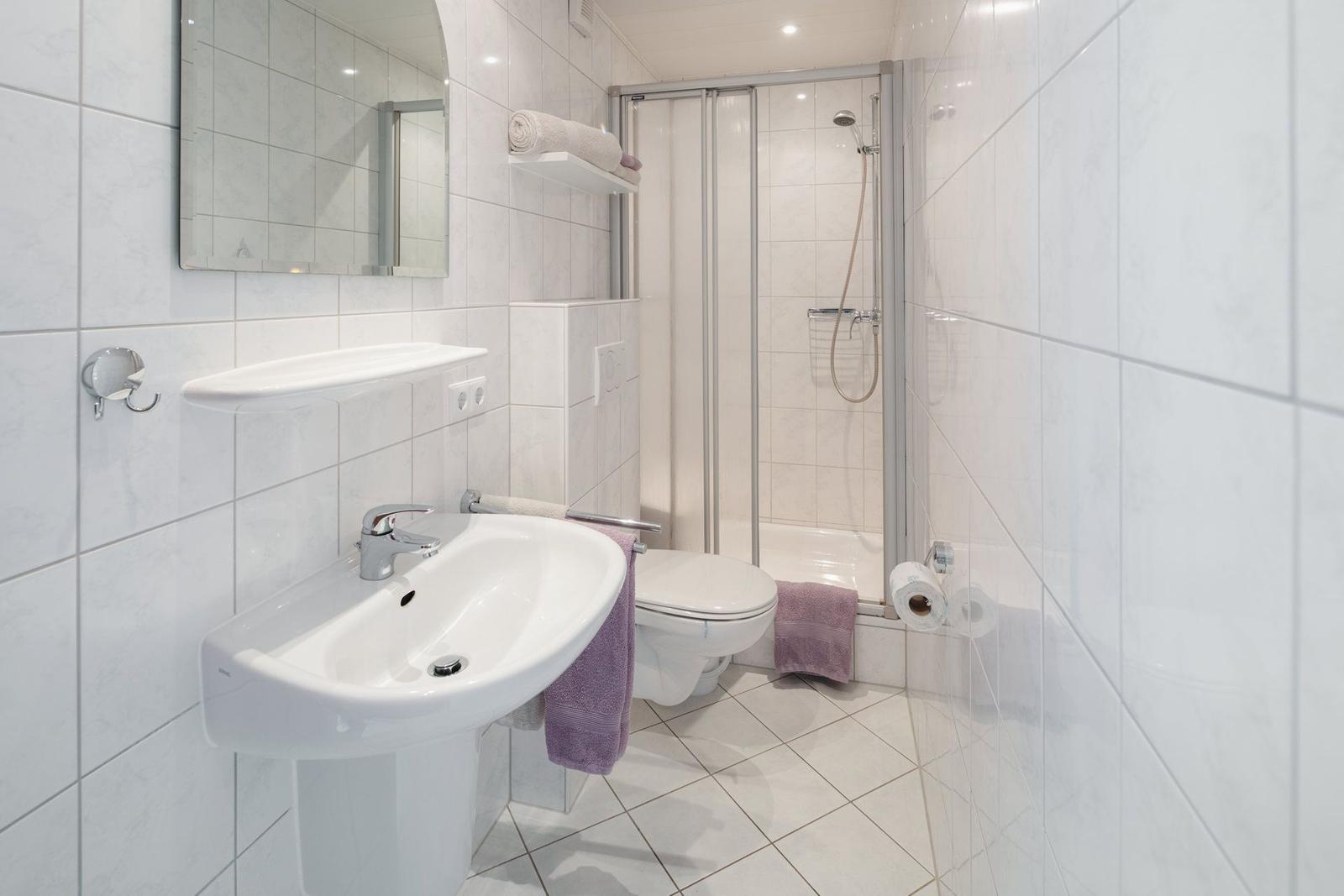 Badezimmer mit Dusche, Toilette und Waschbecken mit Spiegel.