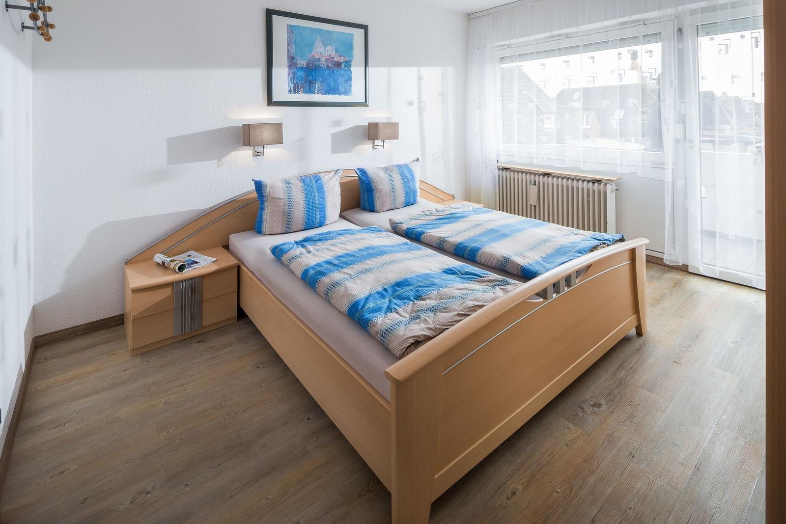 Ein Schlafzimmer mit Doppelbett, Holzmöbeln und Fenster zur Aussicht.