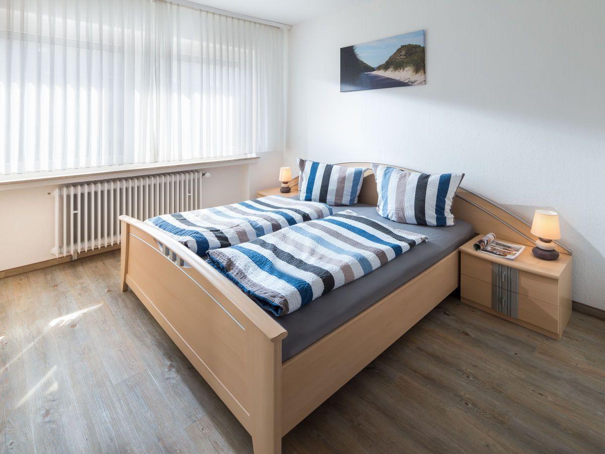 Schlafzimmer mit Doppelbett, Kleiderschrank und Fenster mit Jalousie.