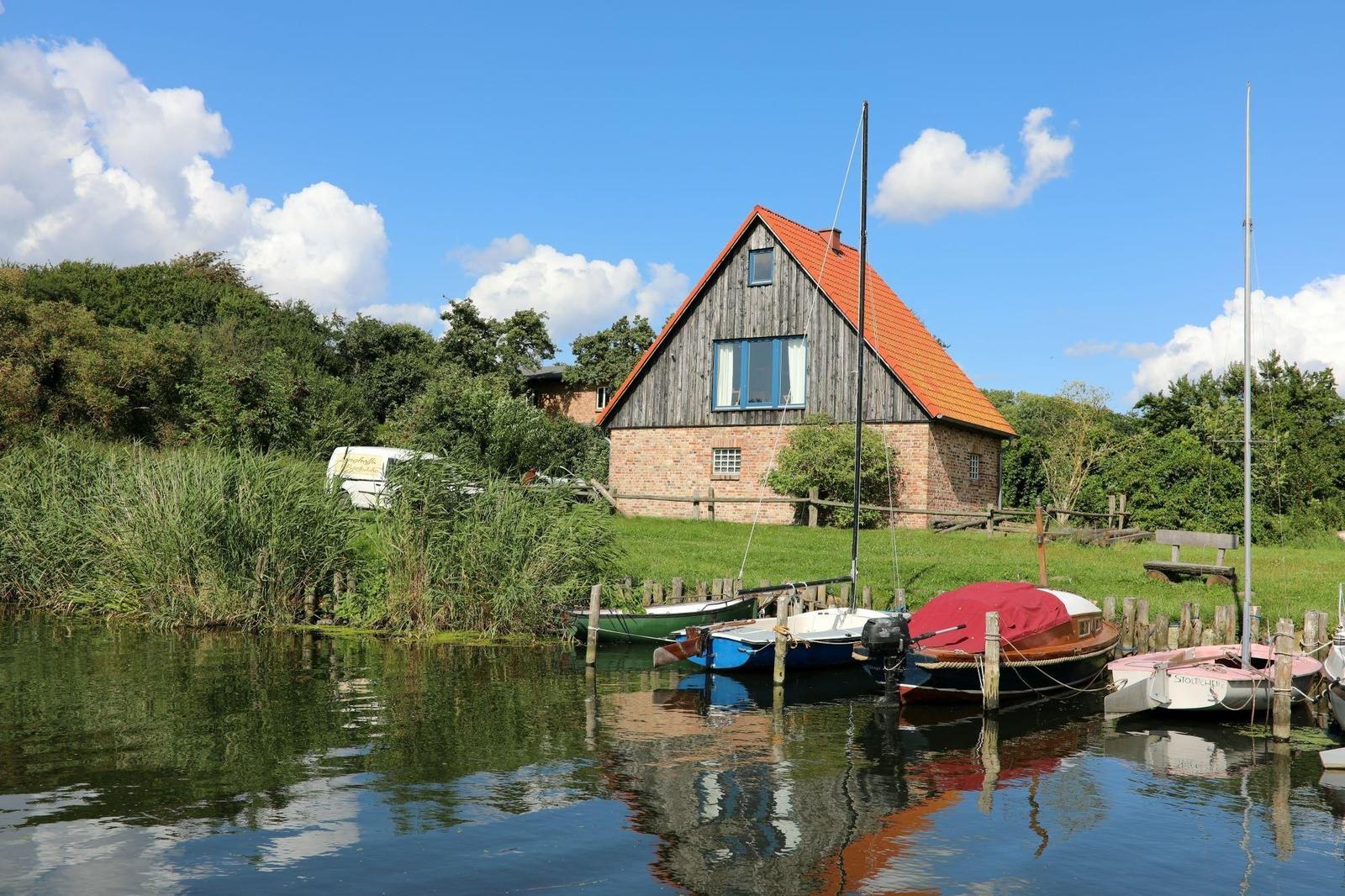 Schloss am Haff mit See und Garten. Traditionelles Gebäude mit rotem Dach.