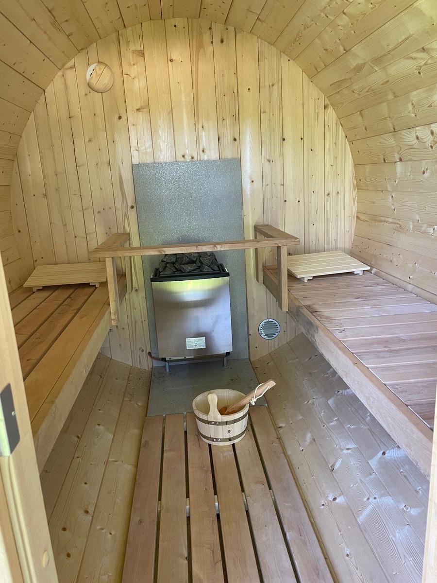 Sauna mit Holzbank, Eingang zur Terrasse und Blick auf grüne Wiese.