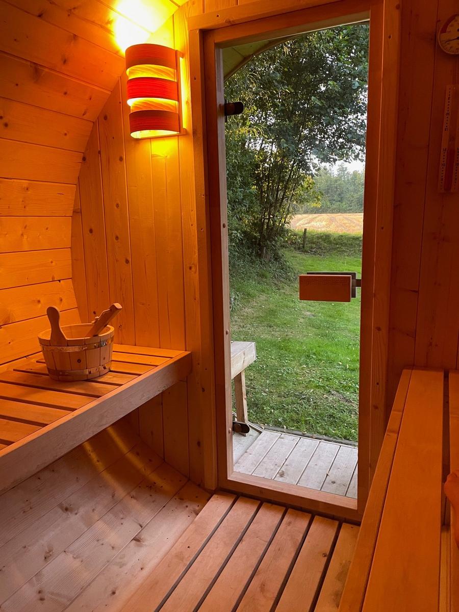 Sonnenuntergang hinter einem Gartenhaus mit Holzstapel und Fahrrädern.