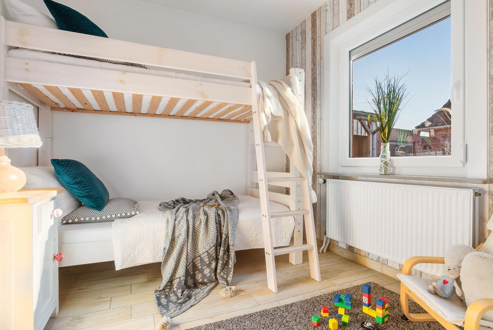 Schlafzimmer mit Doppelbett, Nachttisch und Spielzeug auf dem Boden.