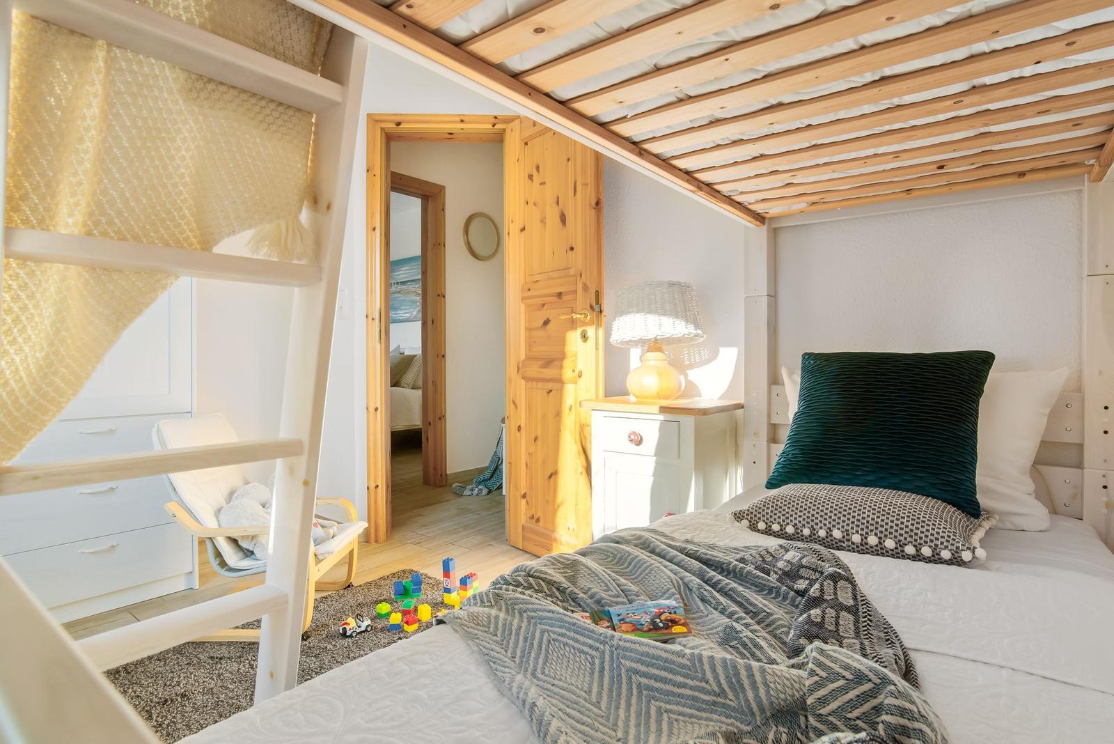 Schlafzimmer mit Bett, Nachttischen und Fensterblick auf Straße.