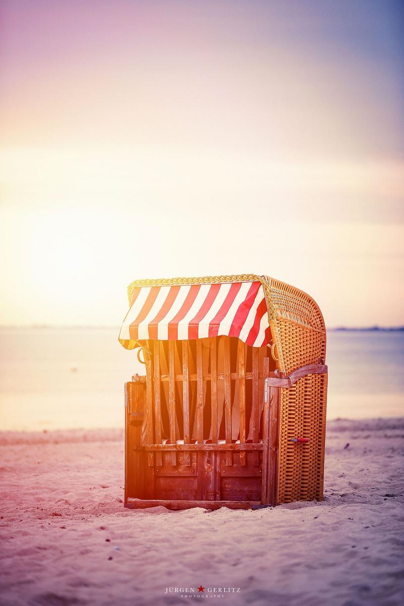 Ein Weg durch gelbe Rapsfelder unter blauem Himmel mit weißen Wolken und Sonne.