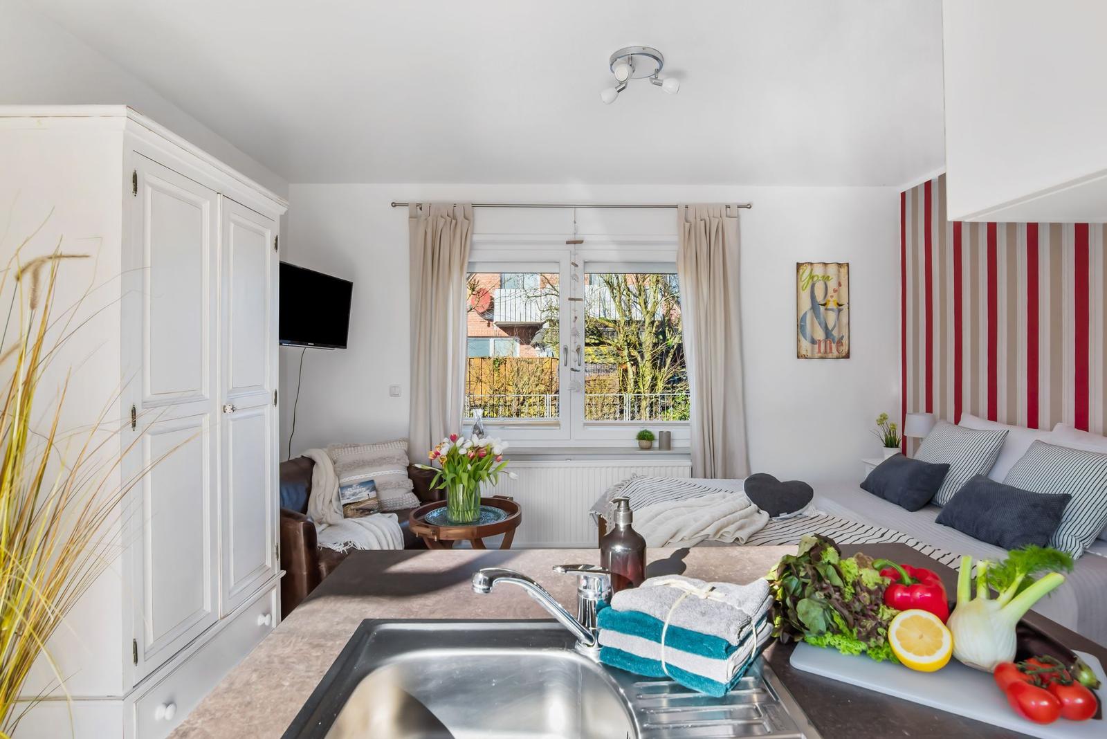 Zimmer mit Bett, Sitzgelegenheit und Fensterblick auf die Straße.