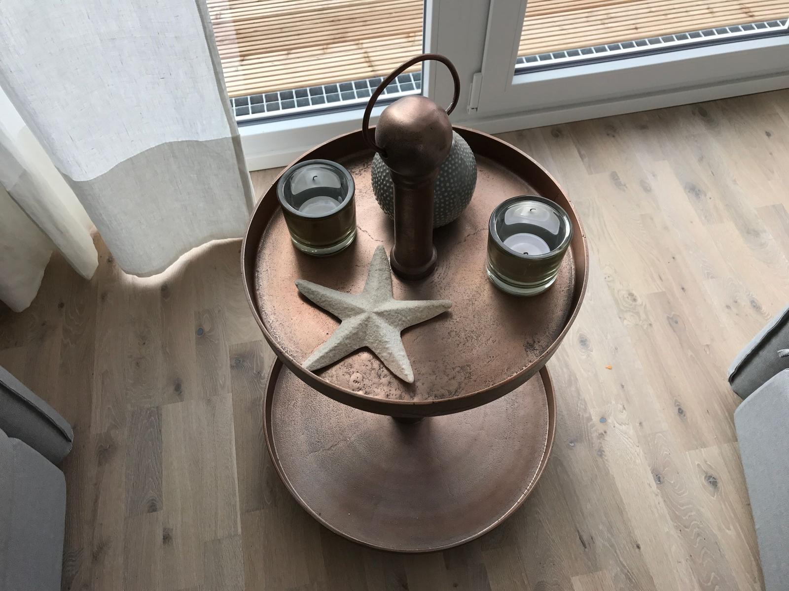 Ein grauer Sessel mit Kissen steht auf Holzboden vor einer Glastür.