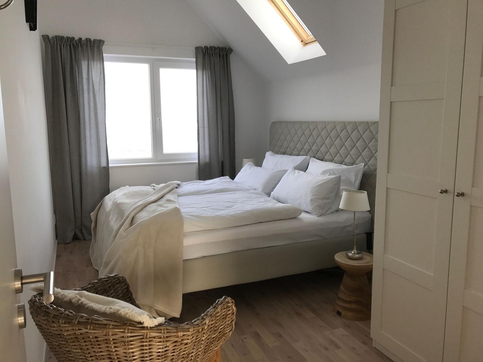 Schlafzimmer mit Bett, Wandbild von Haien und kleiner Ablagefläche.