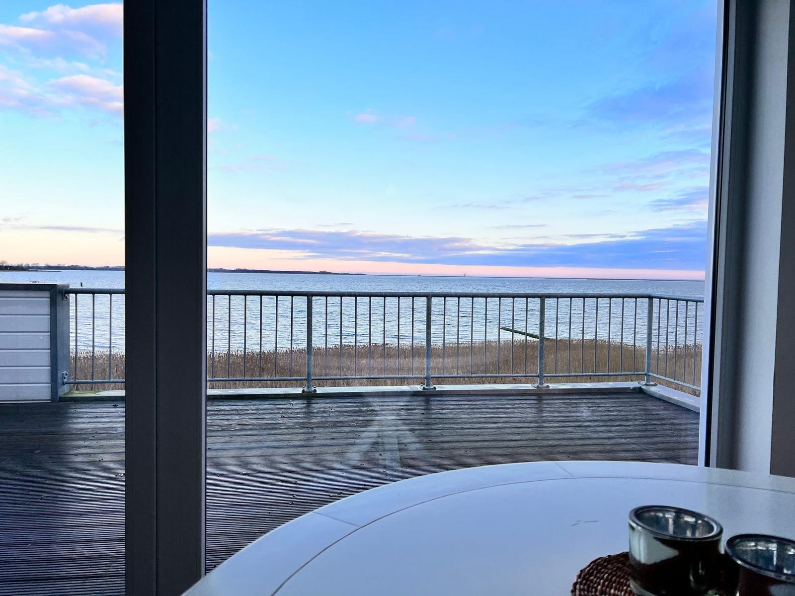 Terrasse mit zwei Holzstühlen und Blick auf das Wasser.