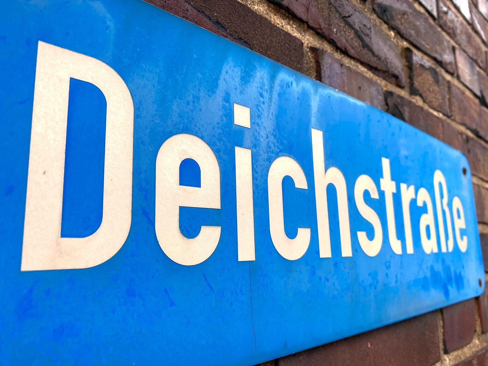 Hafen mit mehreren Booten, darunter ein blaues Schiff mit Mast.