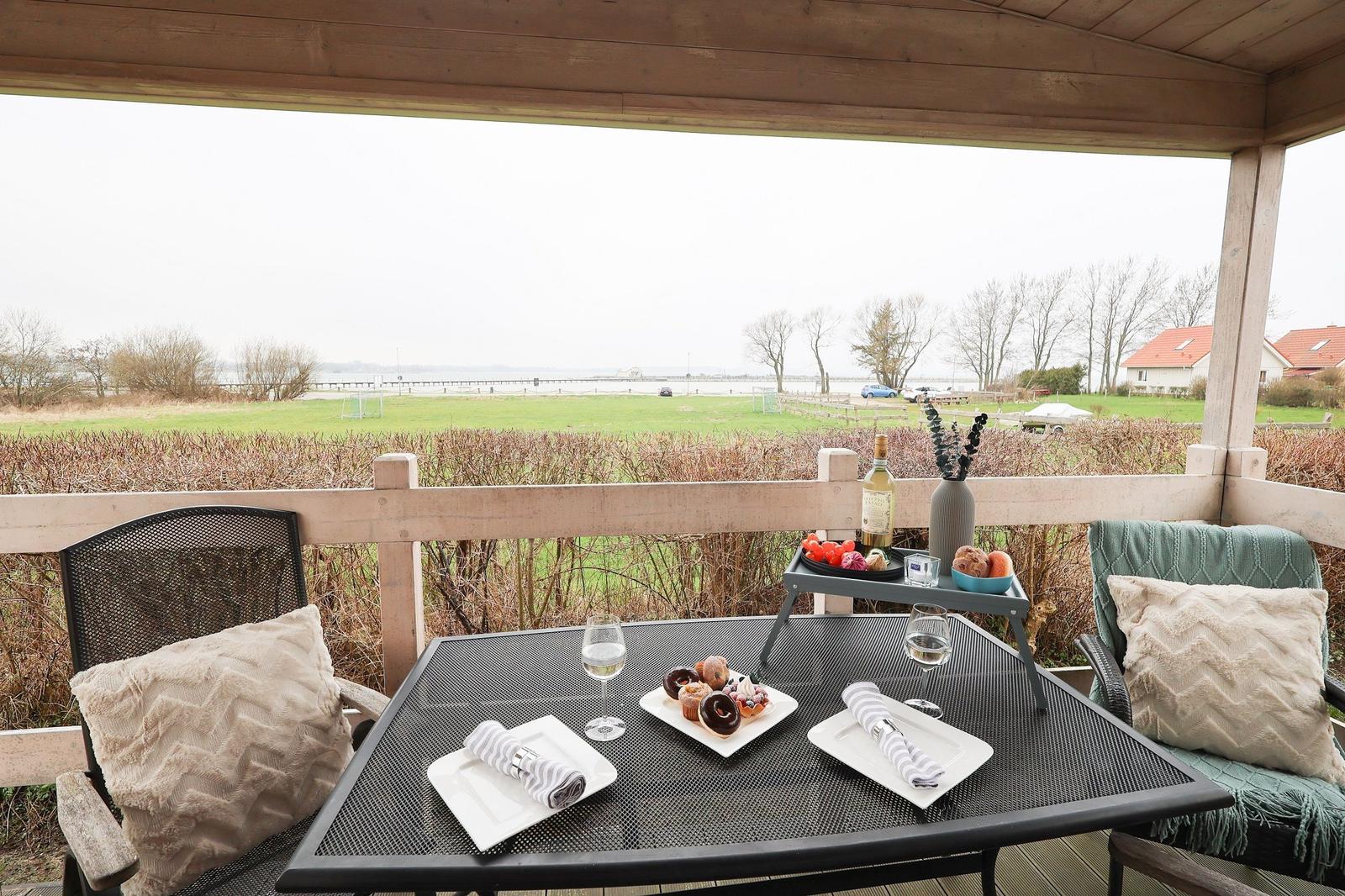 Holiday home with terrace, garden, and wooden railing. Windows with blinds and chimney.