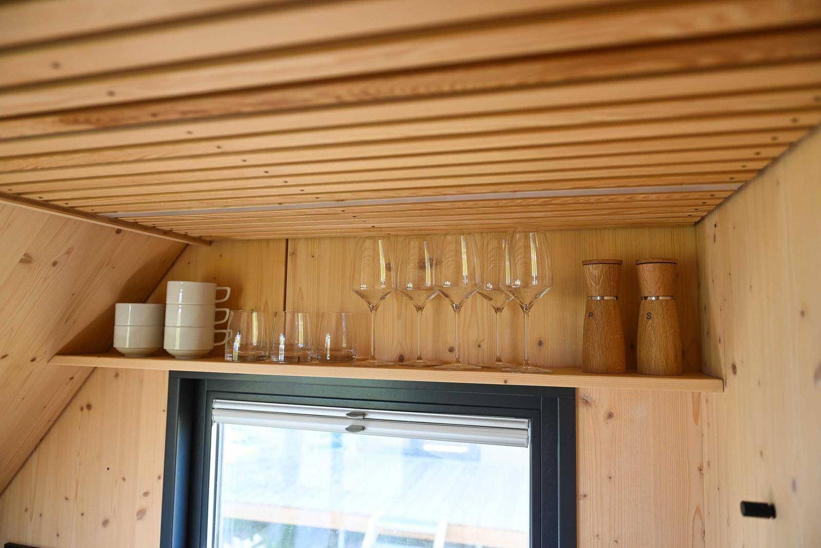 Badezimmer mit Dusche, Waschbecken und Spiegel. Holzwände und dunkle Wandfläche.
