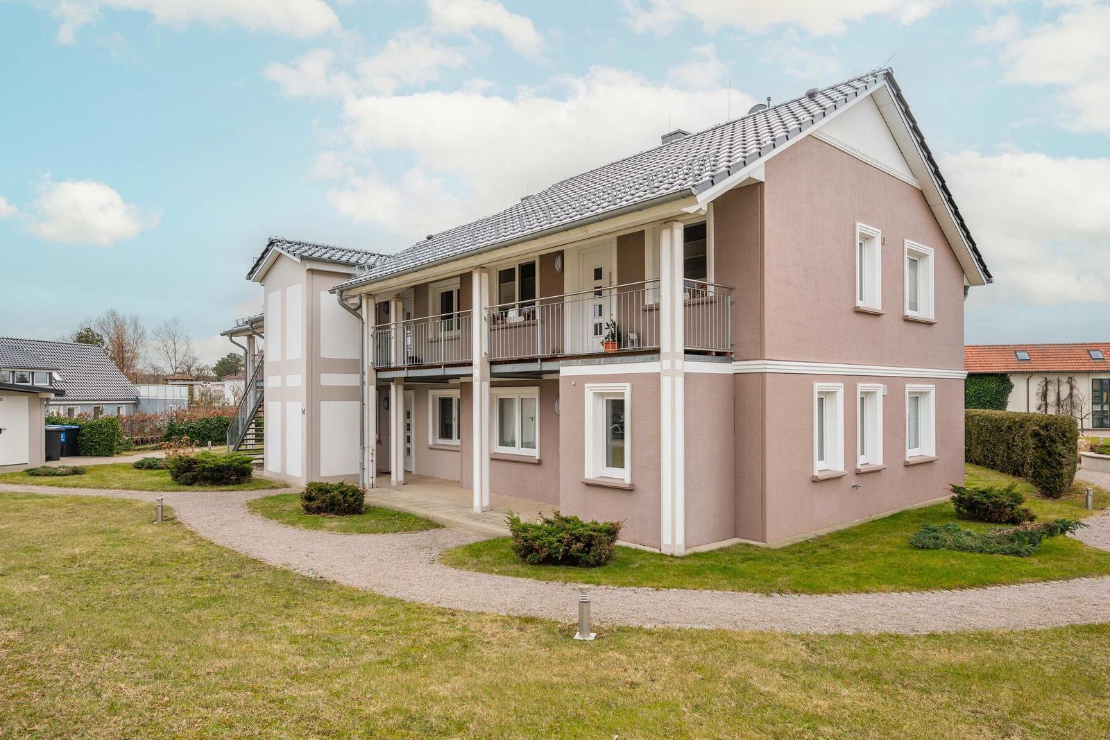 Haus in einem Dorf mit Hafen und Booten. Blick auf Wasser, Wiesen und Wald.