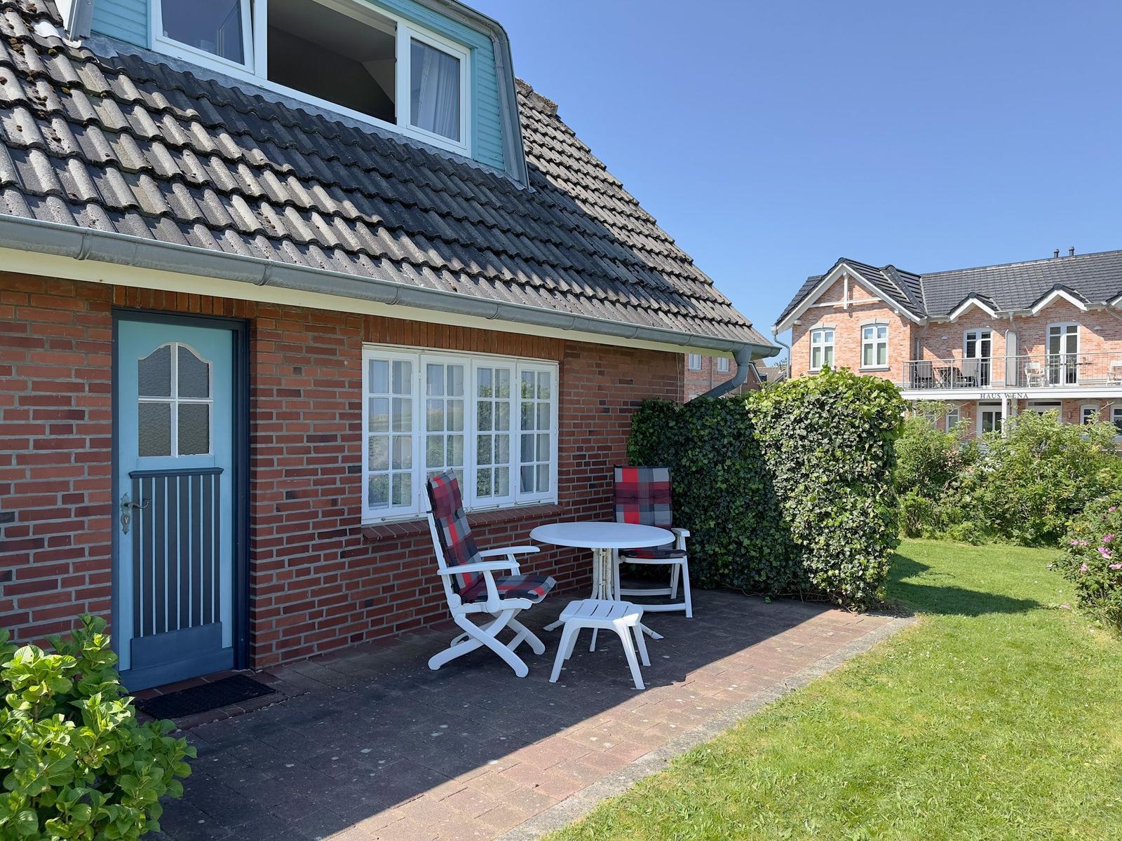 Red brick house with dormers and green garden. Car parked in front.