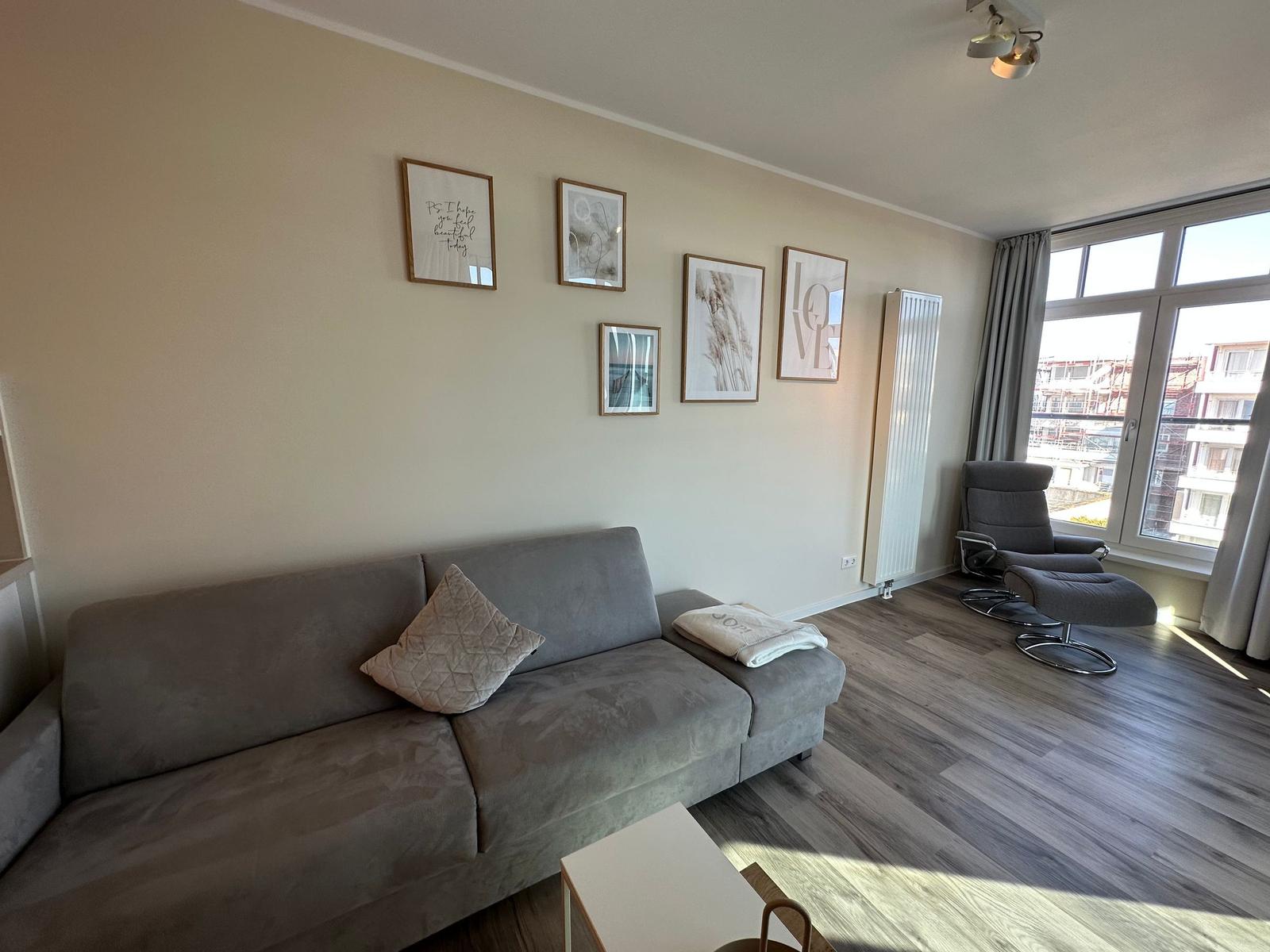 Wohnung mit Essbereich, Küche und Wohnzimmer mit Fenster und Sofa.