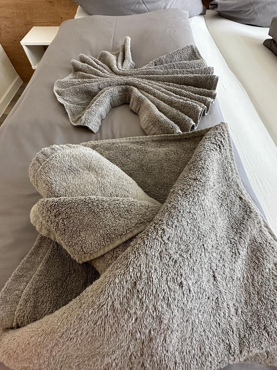 Schlafzimmer mit Doppelbett, Holzwand und Balkonblick.