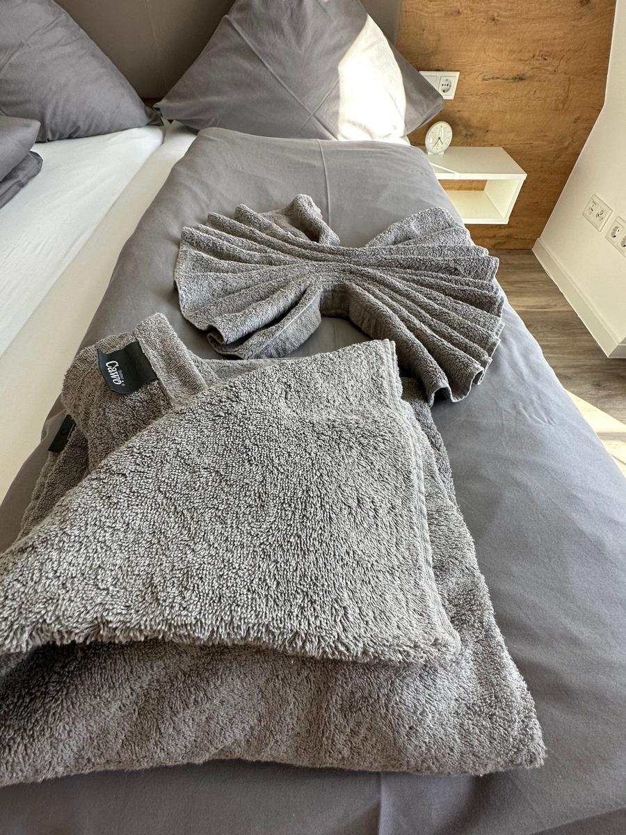 Zimmer mit Doppelbett, Fenster zur Terrasse und Holzboden.