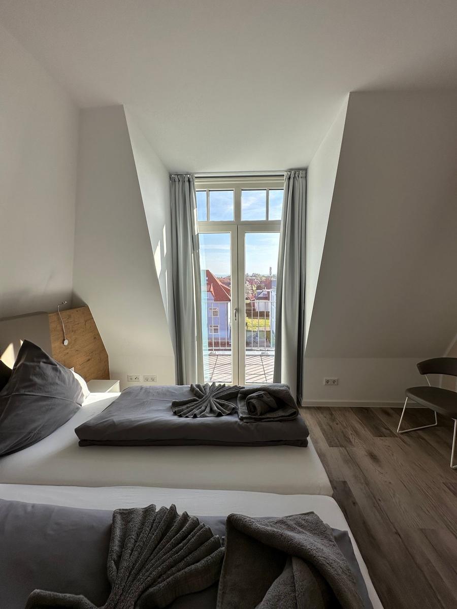 Blick von Balkon auf Wohngebiet mit Häusern und blauem Himmel.