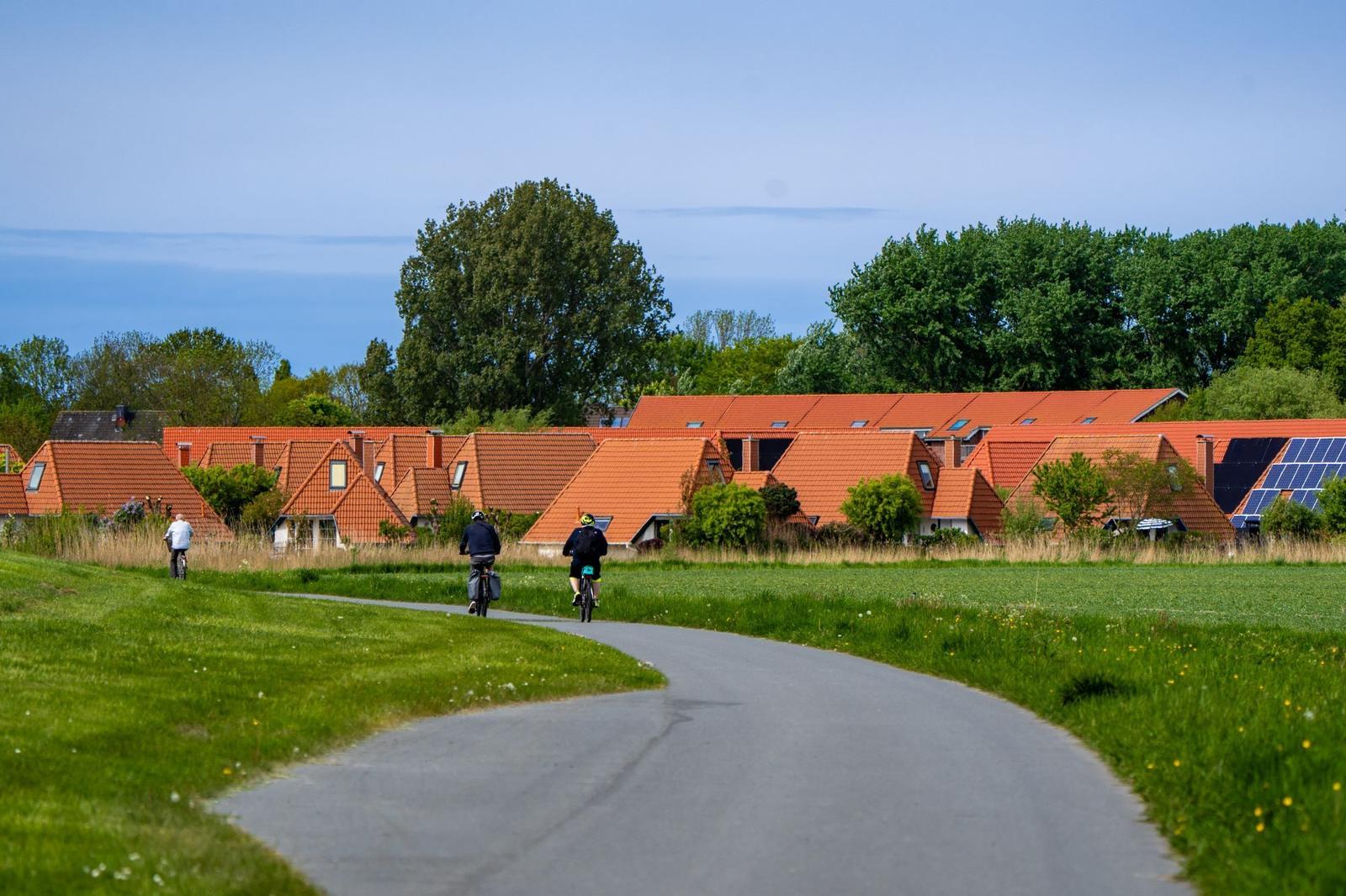 Strandkörbe stehen auf grünem Rasen, im Hintergrund das Wasser und zwei Personen.