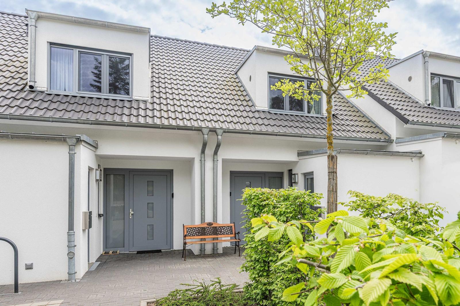 Haus in einer grünen Umgebung mit See und Meer im Hintergrund.