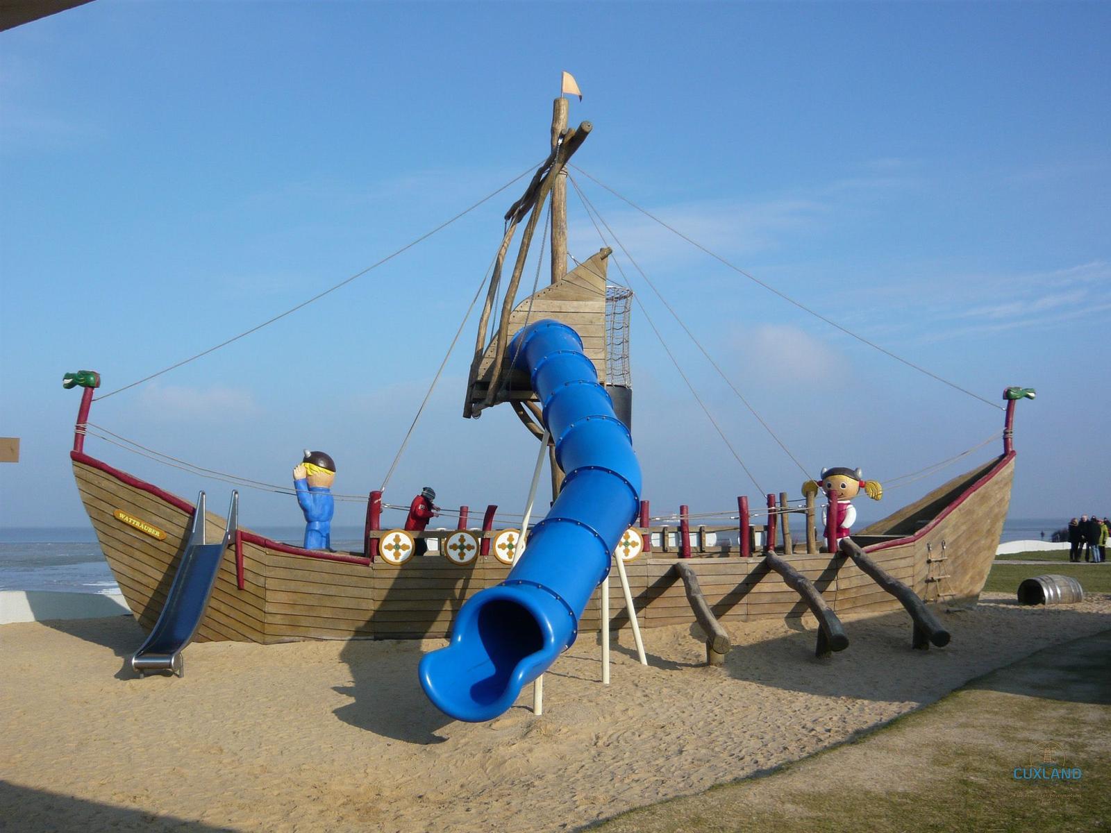 Eine Person sitzt in einem gelben Strandkorb mit blau-weißem Streifenmuster am Strand.