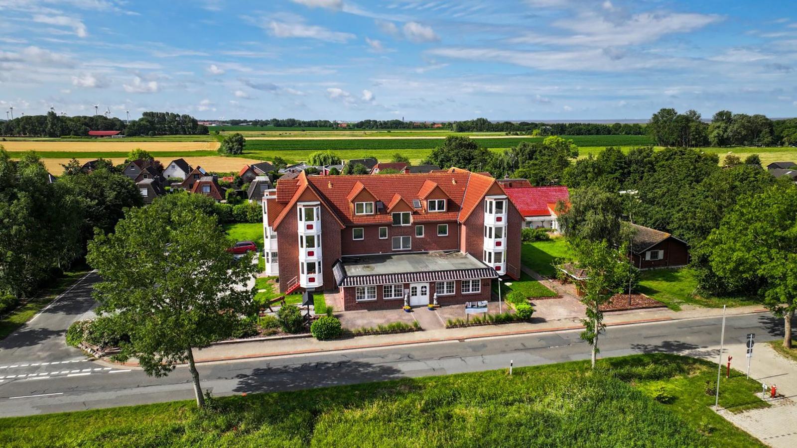 Holzbank an einer Straße mit Blick auf das Meer und grüne Wiesen.