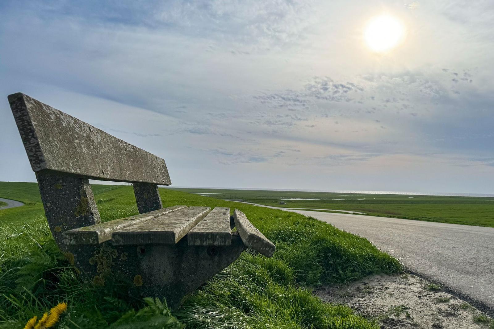 Treppe mit Geländer führt bergauf durch Grasland unter einem bewölkten Himmel.