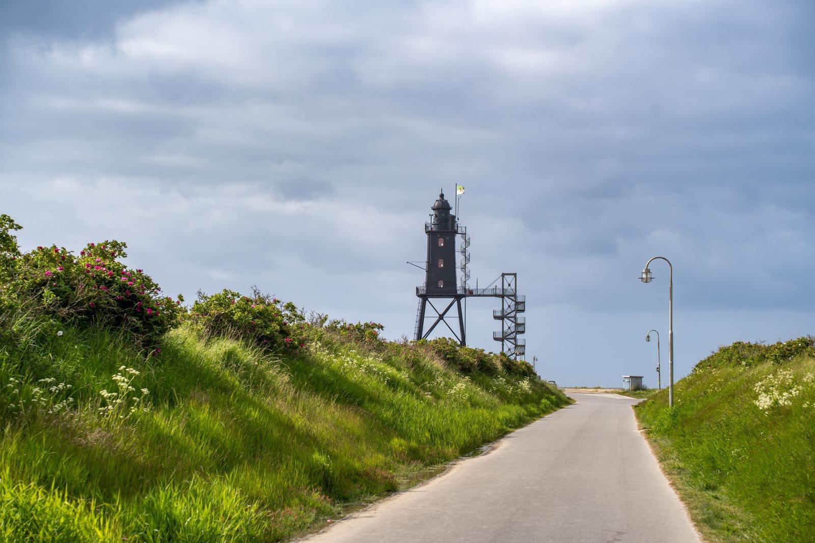 Hafen mit Leuchtturm, Holzpfählen und einem Boot.