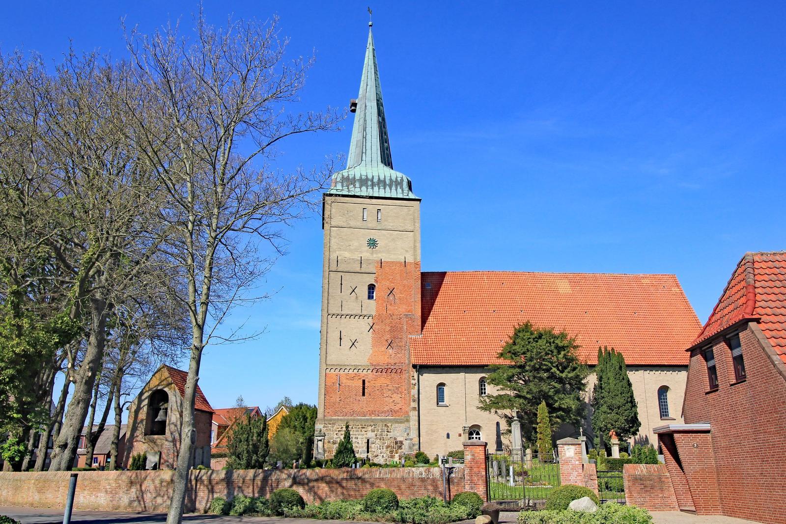 Frostbedeckte Pflanzen rahmen einen schwarz-weißen Leuchtturm mit Blick aufs Meer.