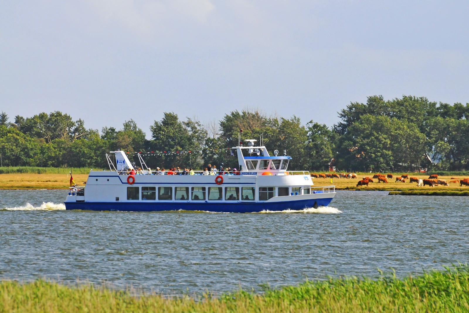 Hafen mit Segelboot und Fähre, Holzsteg, klare See und blauer Himmel.