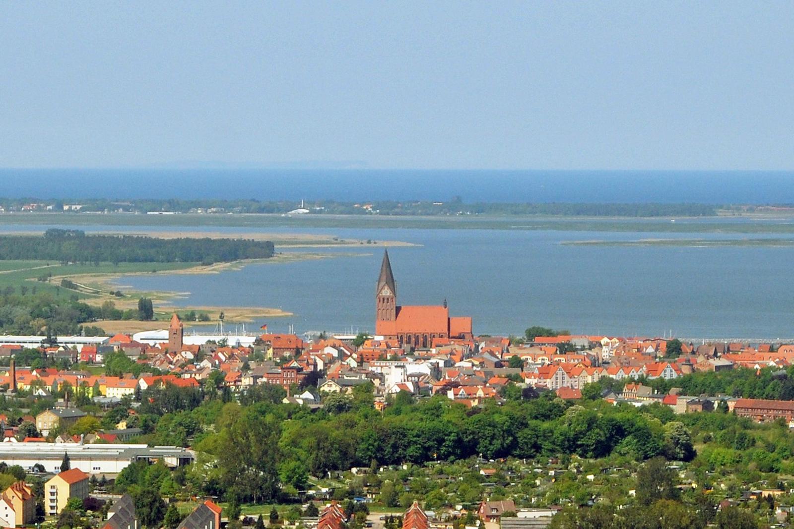Aerial view of a lake with green islands and a village surrounded by forests.