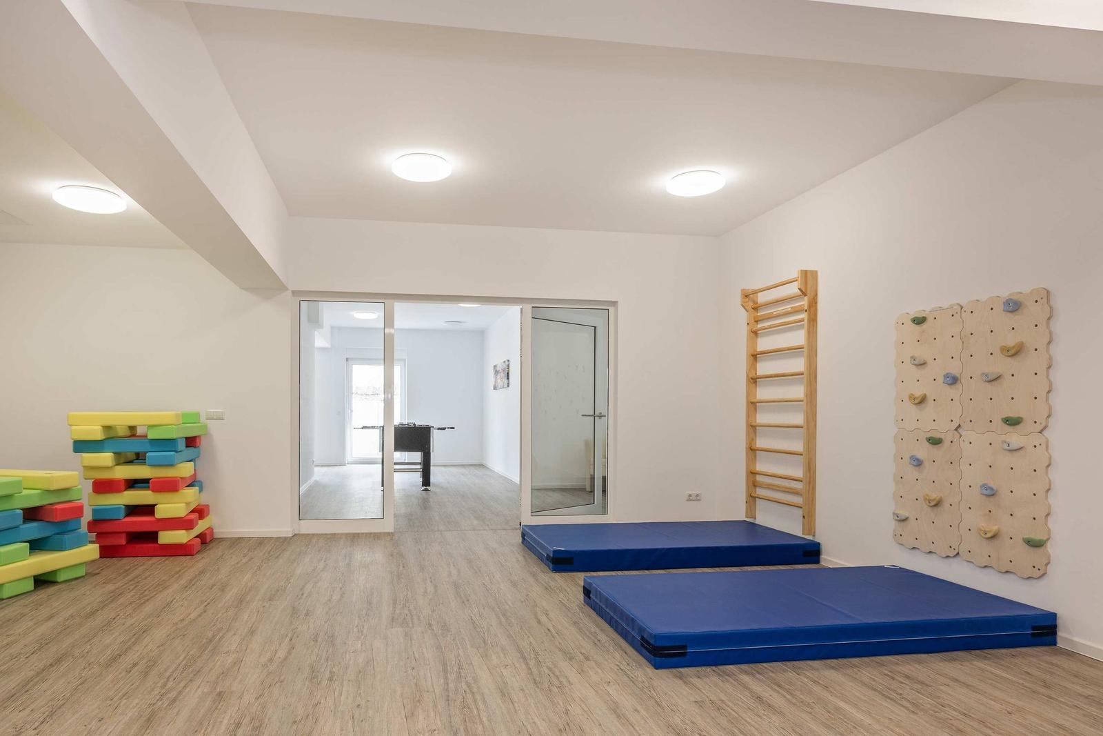 Kinderbereich mit Spielplatz und Wohnhaus im Hintergrund.