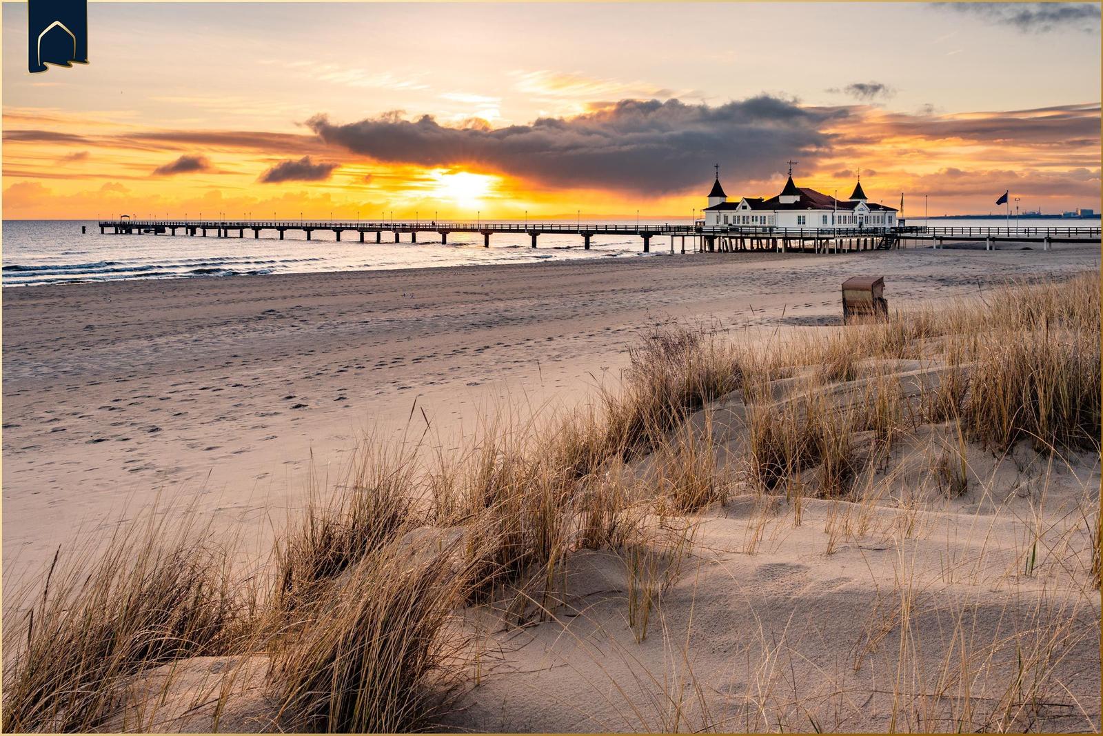 Sandweg durch Gräser zur Küste bei Sonnenuntergang.