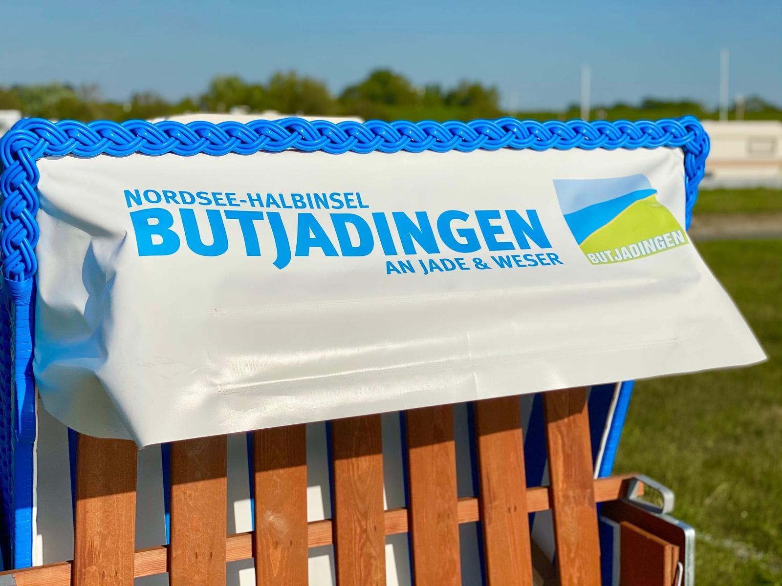 Steigweg mit Skulptur und Wegweiser auf grünem Hang