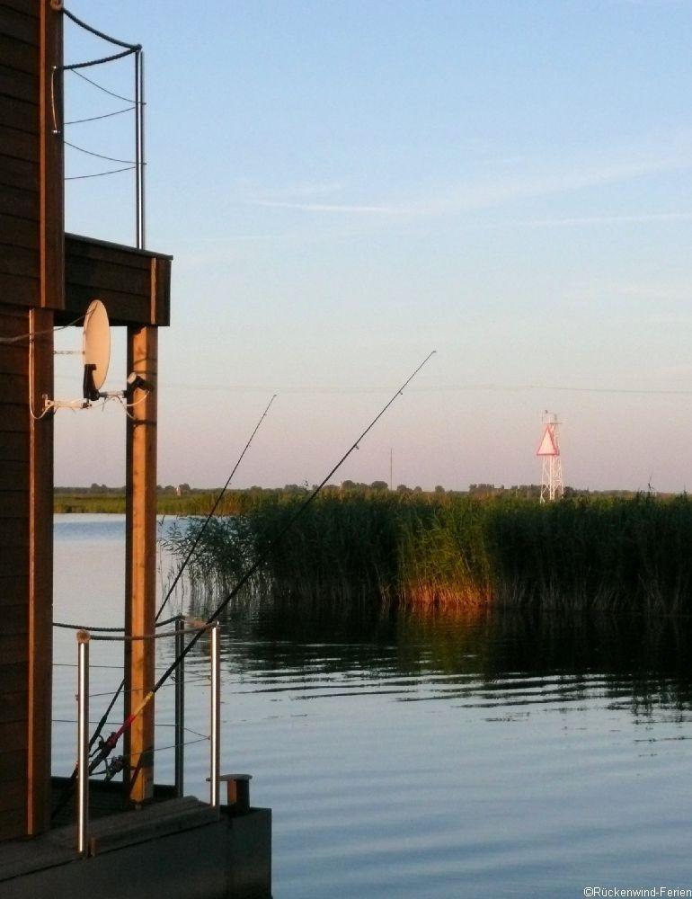 Schiffsanlegestellen mit mehreren gelben Bootshäusern am Wasser.