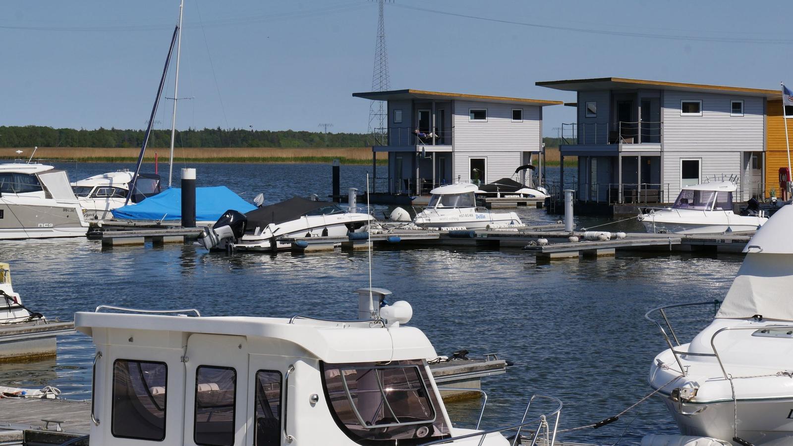 Hafen mit Booten und modernen Wasserhäuschen im Hintergrund.