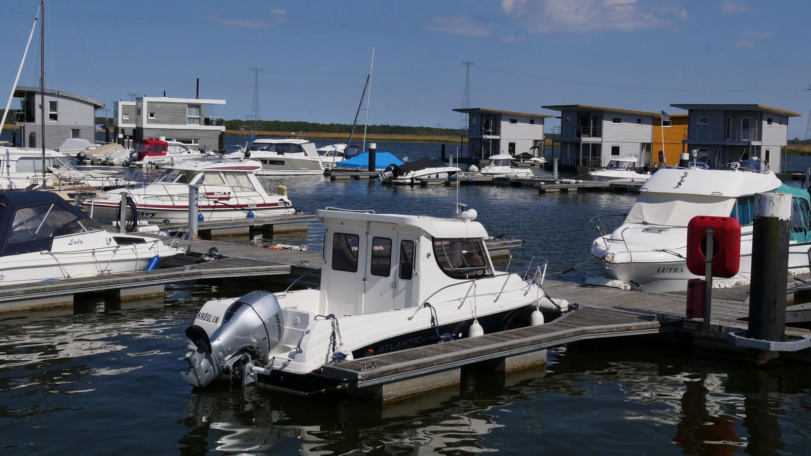 Hafen mit Booten und modernen Stegwohnungen an der Wasserkante.